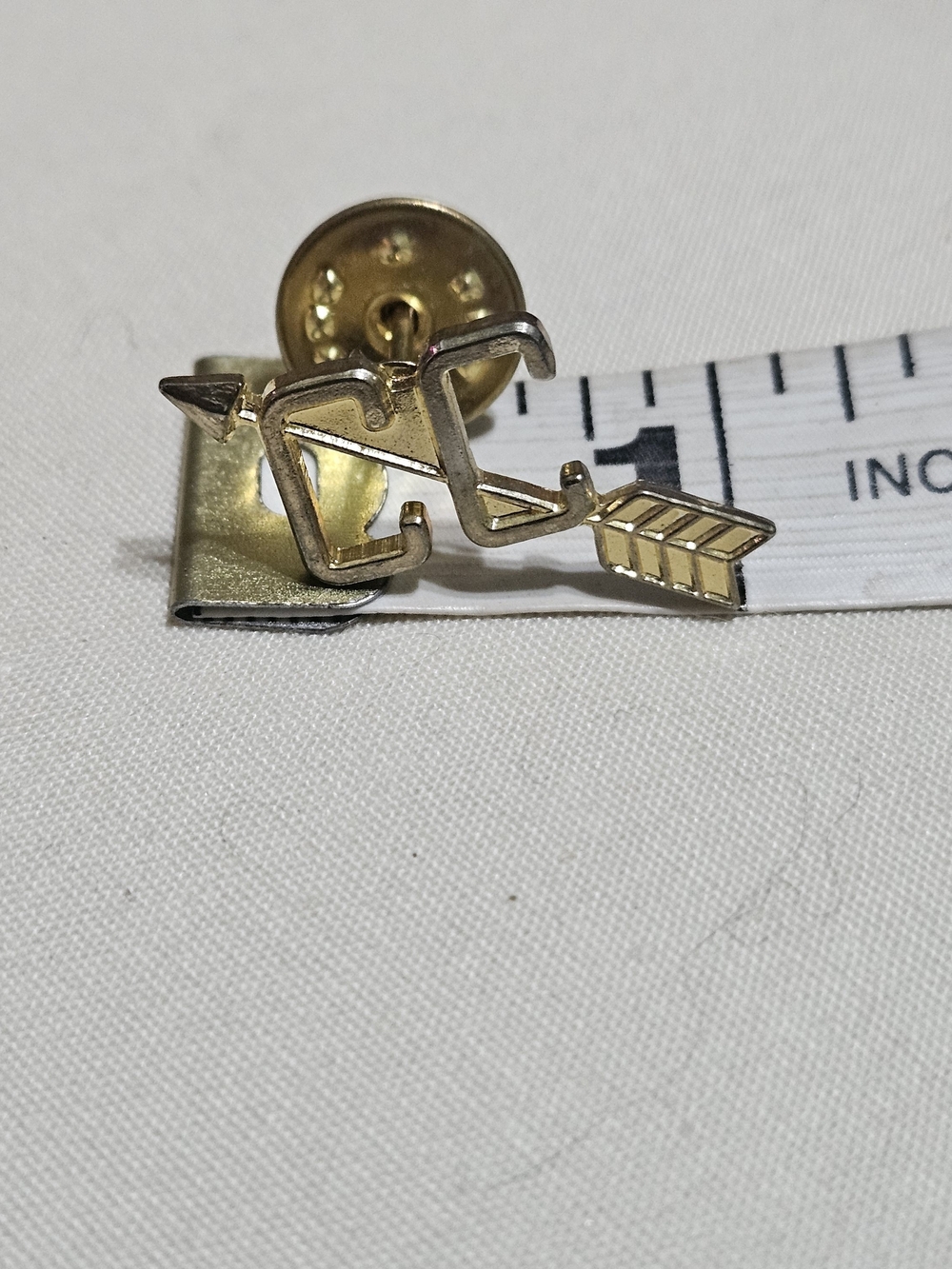 Gold-tone Lapel Pin shaped like an Arrow intersecting a "CC"